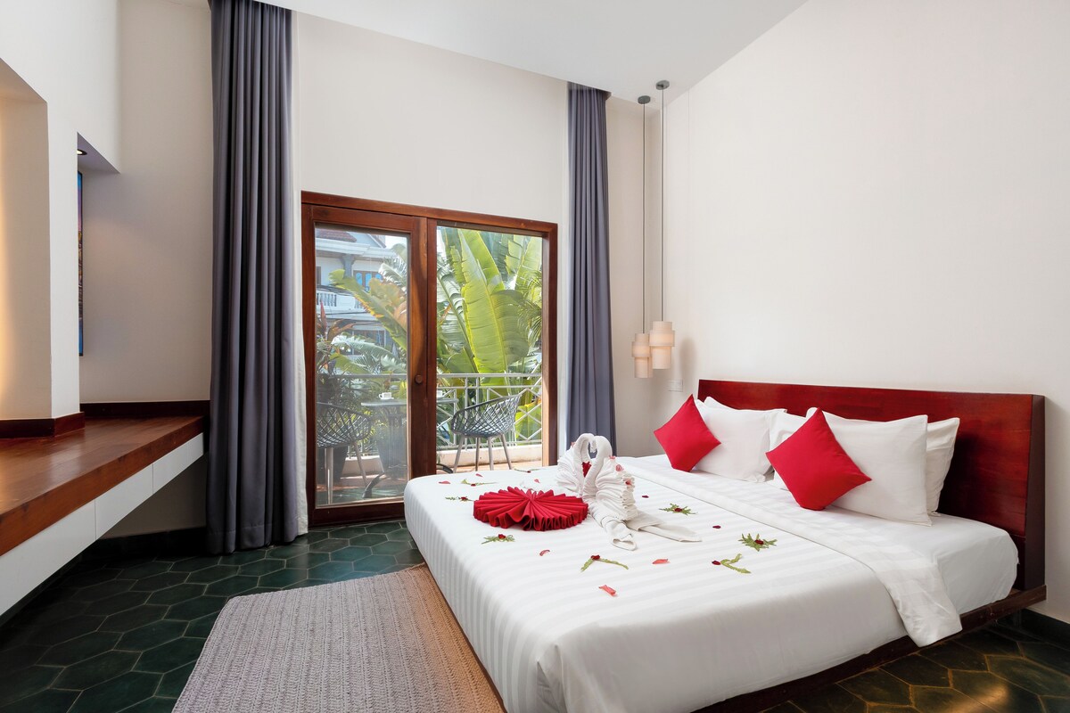 A hotel room with a bed, a view of the outdoors, and a balcony.