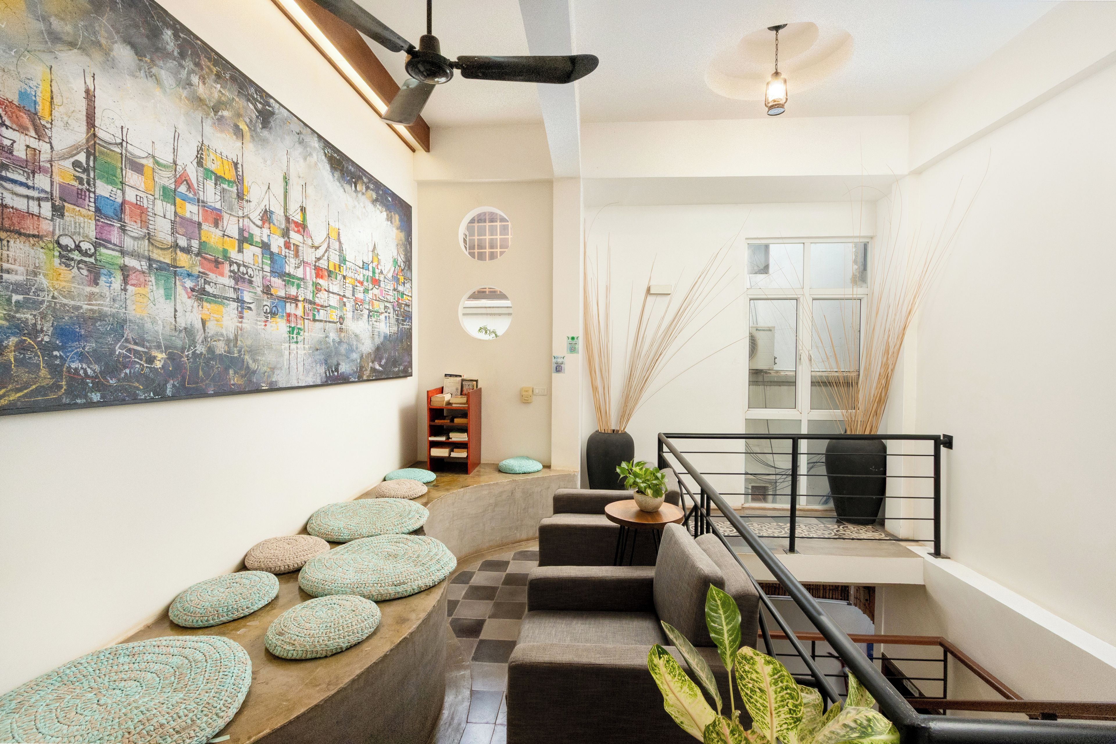 A staircase with a checkered floor, a ceiling fan, a painting, and a bookshelf.