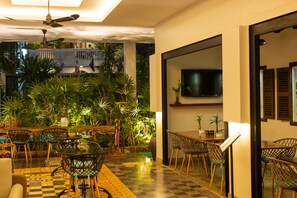 A dining area with a checkered floor, modern chairs, and a ceiling fan. - Baahu Villa (Siem Reap)
