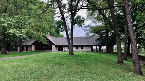 A stone building with a large lawn and trees. - Sunny Cottage: Fire pit, close to biking & walking trails and historic downtown. (Oskaloosa)