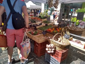 Un puesto de mercado con diversos vegetales y frutas expuestos en cajas y cestas.