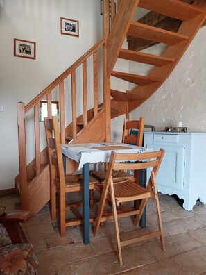 Un escalier en bois, avec une table et des chaises, dans une pièce dotée d’une porte blanche et d’une fenêtre.