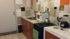 Une cuisine de taille réduite, équipée d’une cuisinière, d’un évier et d’un four à micro-ondes.