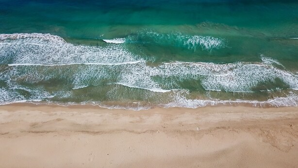 Una playa con agua turquesa cristalina y olas suaves.