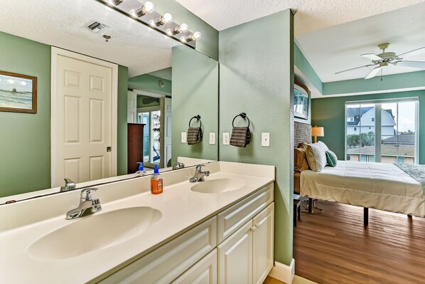 A bathroom with two sinks, a large mirror, and a ceiling fan.