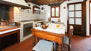 A rustic kitchen with a wooden ceiling, a tiled backsplash, and a dining table with chairs. - Il Mulino di Cecco by Interhome (Vernio)