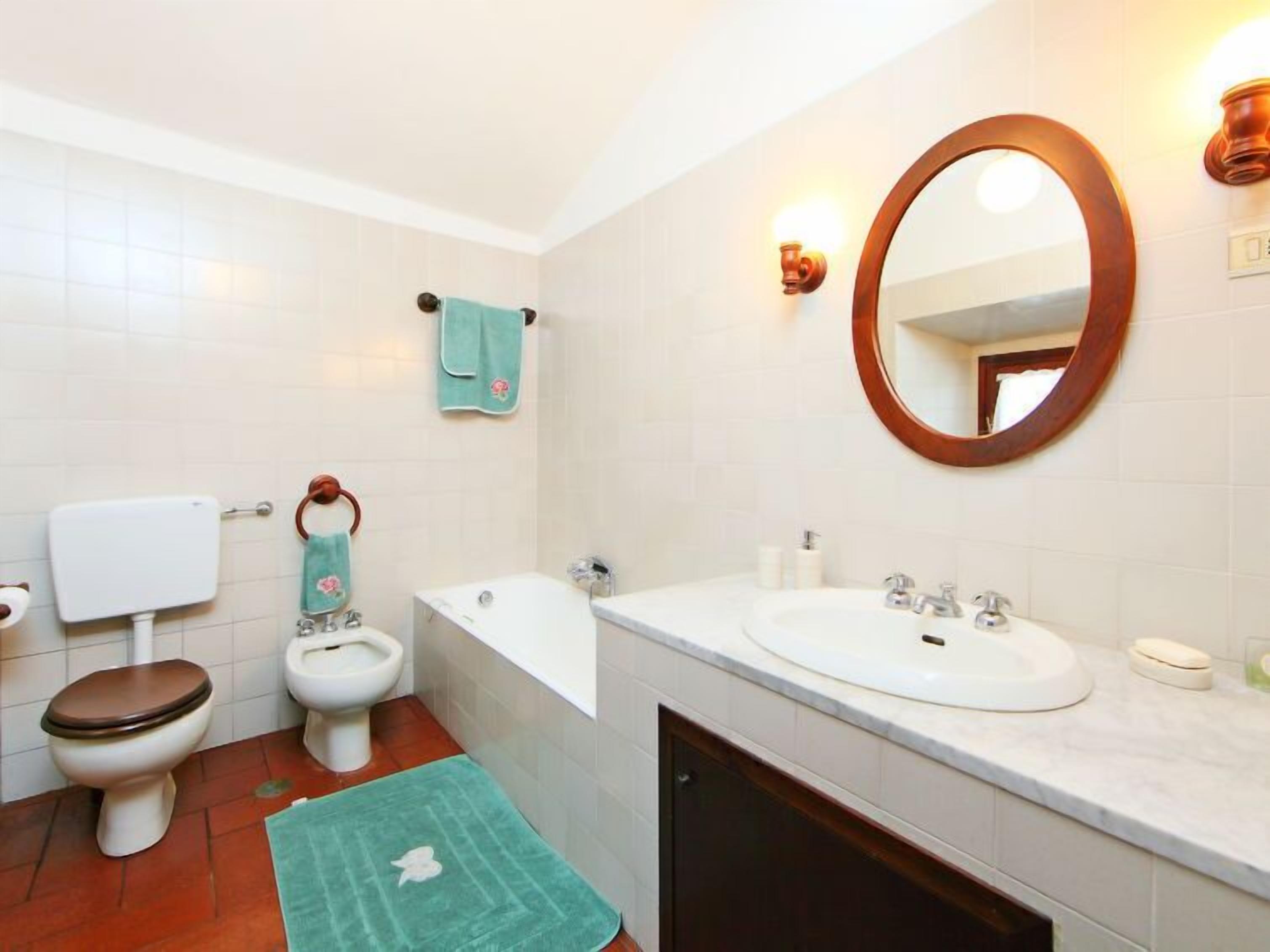 A bathroom with a toilet, bidet, bathtub, and a sink with a mirror.