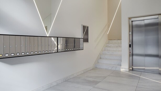 A modern elevator area with a marble staircase and a row of metallic lockers. - Gloria | The Rentals Collection (San Sebastián)