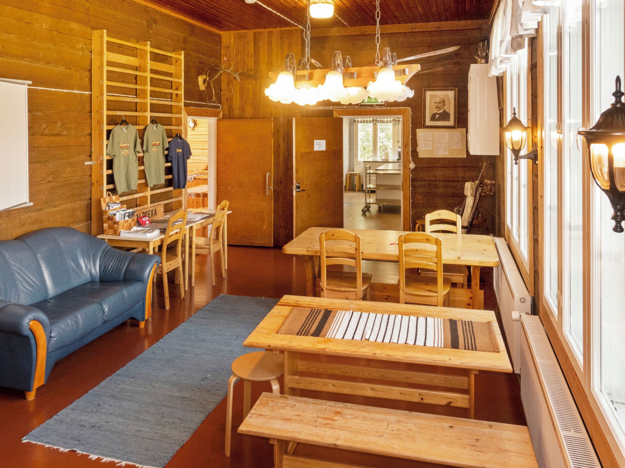 Ein gemütliches Zimmer mit einem Holztisch, Stühlen, einem blauen Sofa und einer Pendelleuchte.
