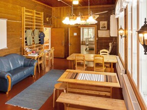 Una habitación acogedora con una mesa de madera, sillas, un sofá azul y una lámpara colgante.