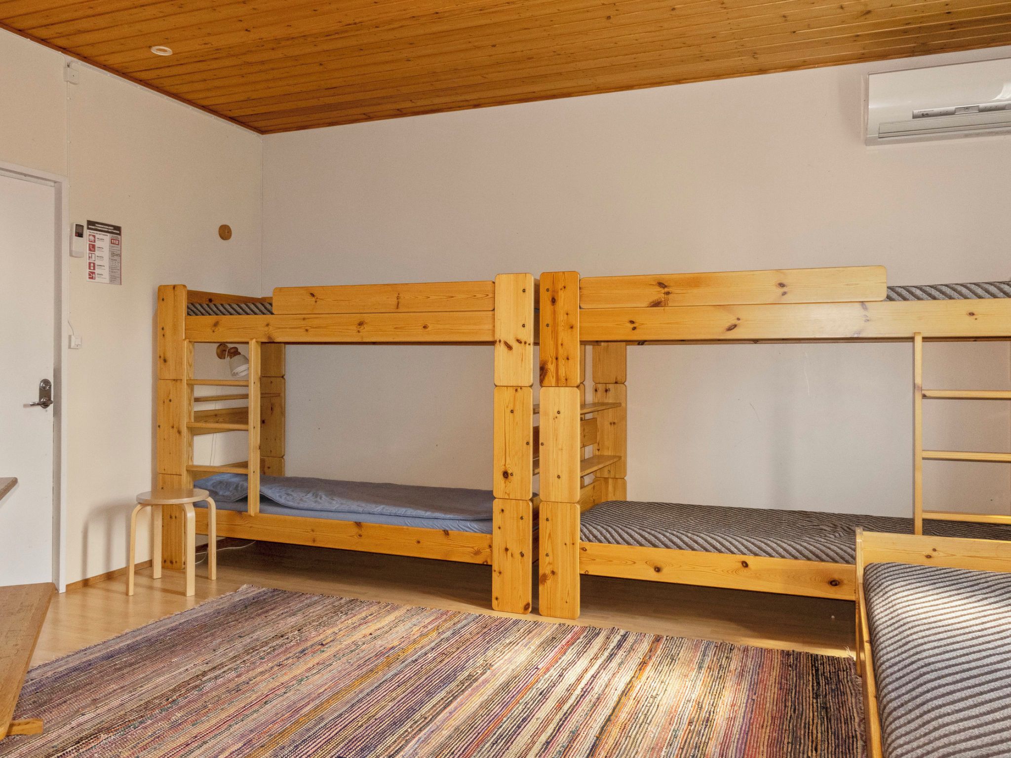 Quarto com beliches, uma mesinha e um tapete estampado.