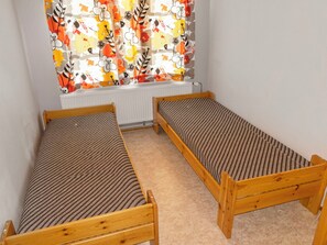 Una habitación con dos literas de madera, un radiador y una ventana con cortinas coloridas.