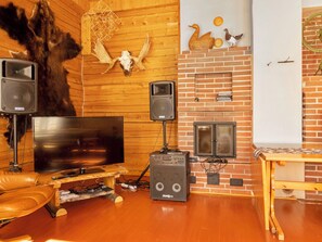 Una sala de estar acogedora con una pared de madera, una chimenea, un televisor y un equipo de sonido.