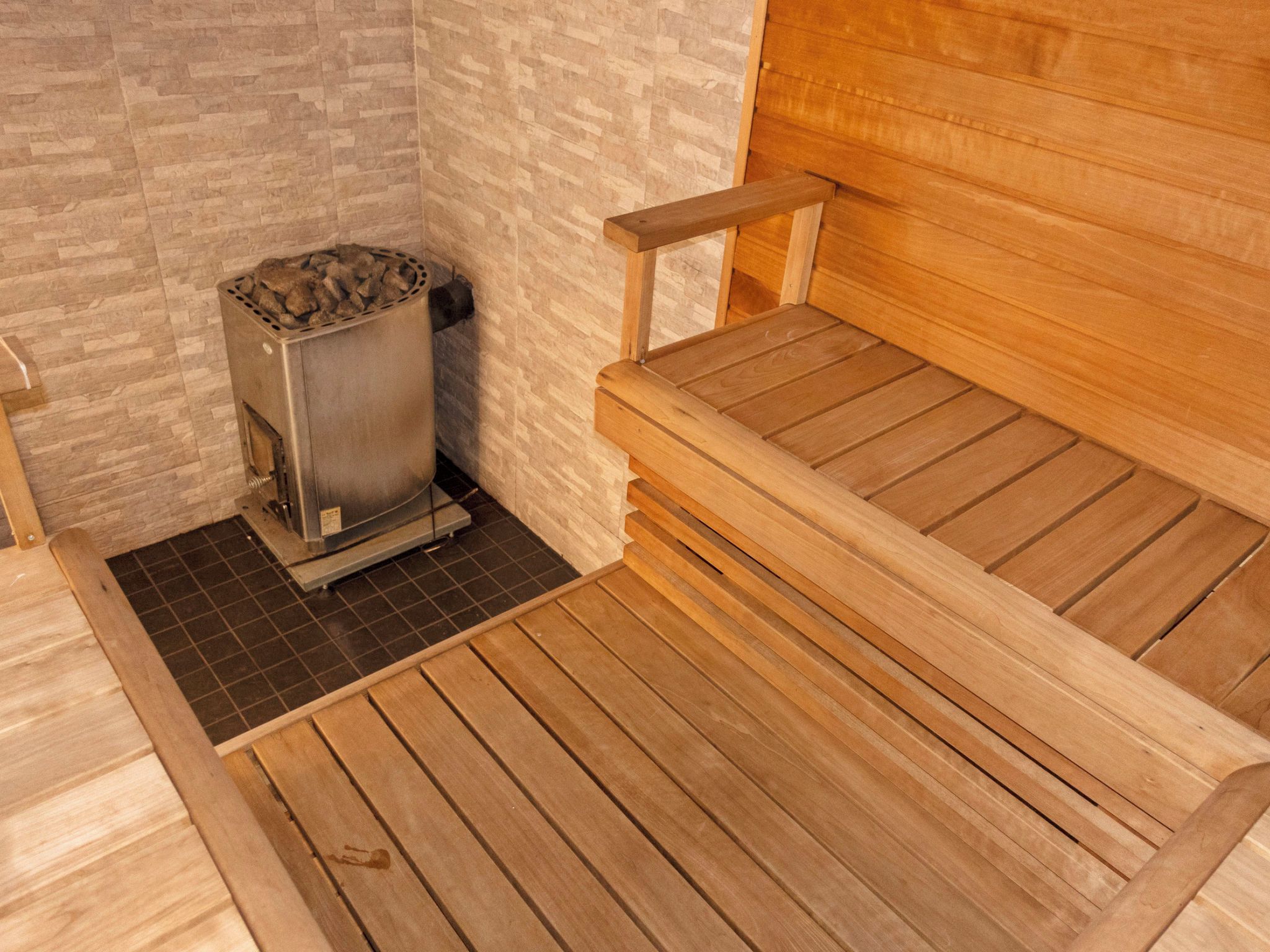 Eine Sauna mit einer Holzbank und einem Metallofen.