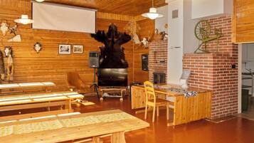 A rustic interior with wooden walls, a brick fireplace, and a large bear sculpture.
