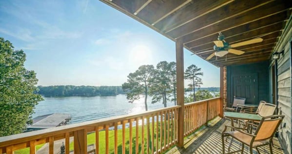 Enjoy a serene lakeside view from this deck, complete with comfortable seating and a table.
