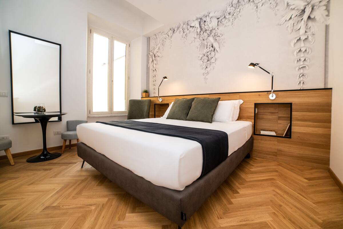 A modern bedroom with a large bed, a desk, and a chair.