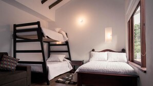 Une chambre avec un lit superposé, un lit simple, un canapé et une fenêtre avec des rideaux.