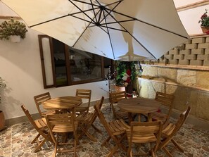 Un patio con una mesa y sillas de madera redondas, una sombrilla y un muro de ladrillo.