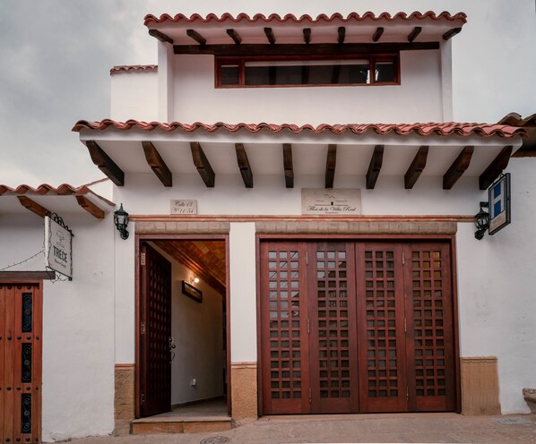Un edificio con techo de tejas, puerta de madera con paneles de vidrio y un letrero que indica que es un hotel.