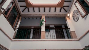 L’intérieur d’un bâtiment, avec une horloge, un pot de fleurs et une balustrade de balcon.