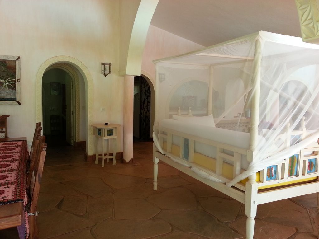 Un dormitorio con una cama con dosel, una mesita y una silla.