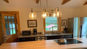 A kitchen with a wooden countertop, a kettle, a coffee maker, and a refrigerator.