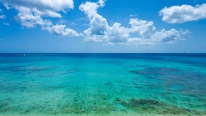 Une plage à l’eau turquoise et limpide, bordée d’un rivage sablonneux.
