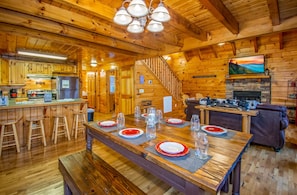 L’intérieur d’un chalet rustique en bois comprend un coin repas aménagé pour quatre personnes, une cuisine équipée et une cheminée.