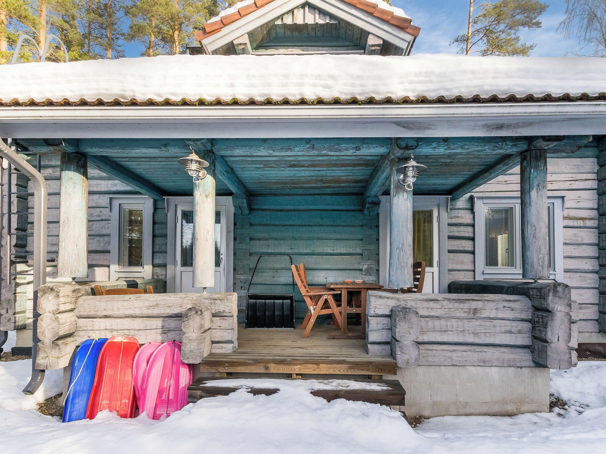 A wooden cabin with a porch, a table, and chairs.