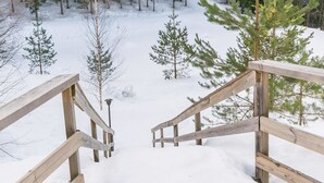 A wooden staircase leading down to a snowy forest area with trees. - Vesan villa by Interhome (Sysmä)