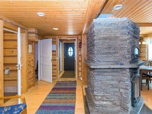 A log cabin interior with a stone fireplace, wooden walls, and a hallway leading to a door. - Vesan villa by Interhome (Sysmä)