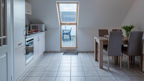 Una cocina moderna con armarios blancos, un microondas y un comedor con mesa y sillas.