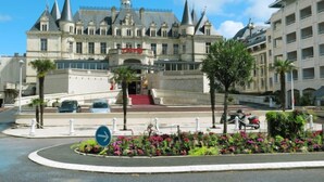 A grand hotel with a prominent entrance, a red staircase, and a landscaped garden with tropical plants. - Apartment Hunier by Interhome (Arcachon)