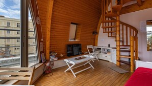 A cozy cabin with a wooden interior, a fireplace, a TV, and a spiral staircase. - Apartment Hunier by Interhome (Arcachon)