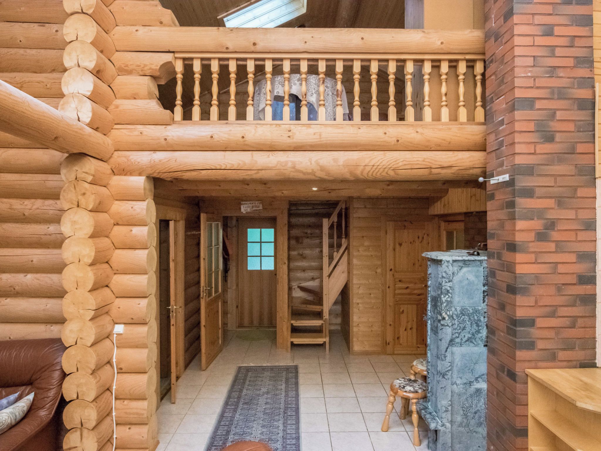 L’intérieur d’une cabane en rondins, avec un escalier en bois, une cheminée et un coin salon confortable.