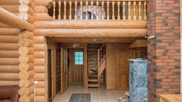 A log cabin interior with a wooden staircase, a fireplace, and a cozy seating area.