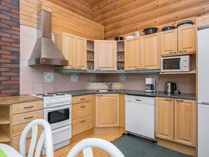 Une cuisine de taille réduite, dotée de meubles en bois, d’une cuisinière, d’un four à micro-ondes et d’un lave-vaisselle.