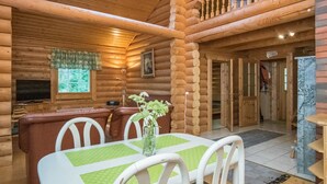 Ein Blockhaus-Interieur mit Essbereich, Fernseher und Balkon.