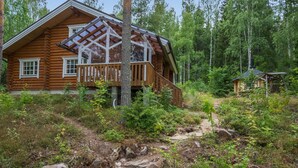 Eine Blockhütte mit Veranda, umgeben von dichtem Wald und einem Steinweg.