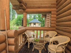 A wooden log cabin with a balcony featuring wicker chairs and a glass table. - Neitlinna by Interhome (Mikkeli)