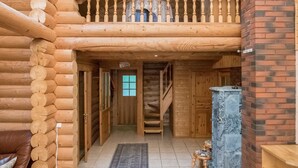 Ein Holzblockhaus-Interieur mit einer Holztreppe, einem Balkon und einem Kamin.