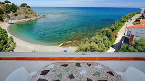 A coastal view from a balcony with a clear sea, a sandy beach, and a residential area with houses and greenery. - Puerto De La Selva by Interhome (Llançà)