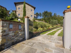 Un bâtiment en pierre avec un chemin pavé menant à une entrée fermée par un portail.