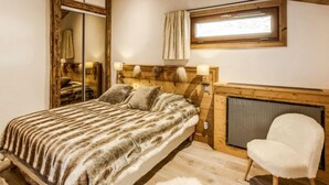A bedroom with a bed, a chair, a window, and a fireplace. - Grand Roc (Val Claret) by Interhome (Tignes)