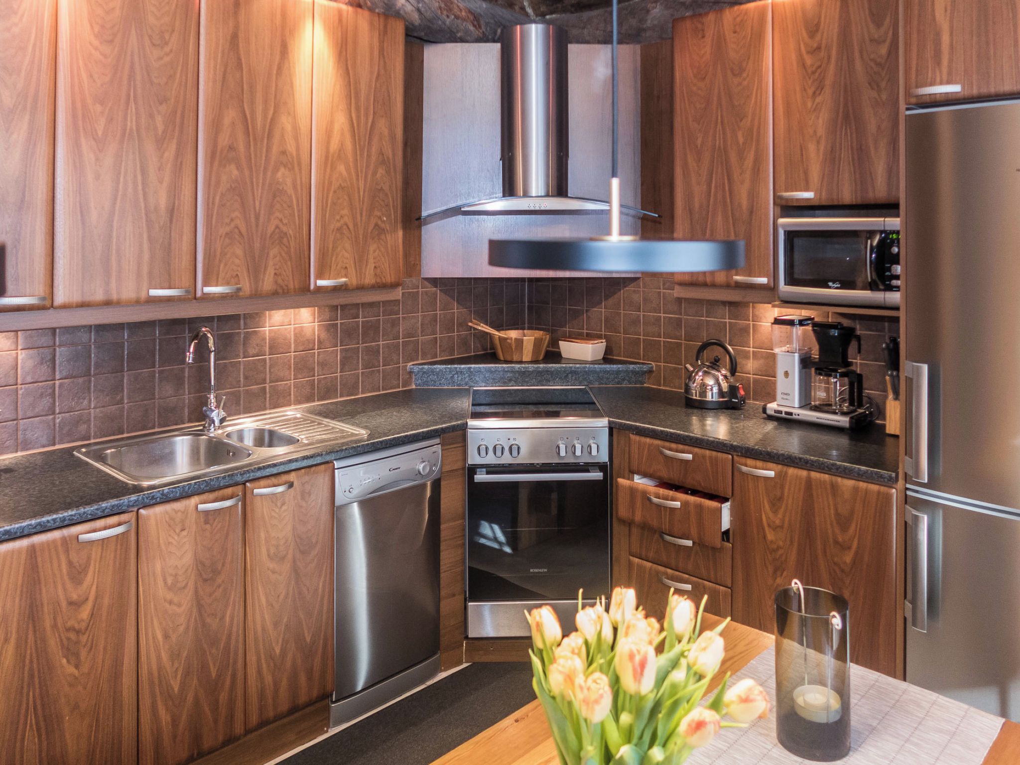 A modern kitchen with wooden cabinets, stainless steel appliances, and a tiled backsplash.