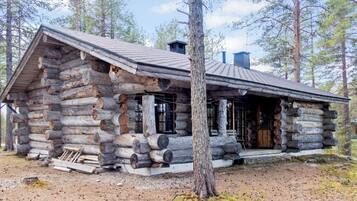 Une cabane en rondins avec une véranda, une cheminée et une fenêtre.