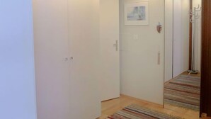 A hallway with a wooden floor, white walls, and a door with a small picture on it. - Appartmenthaus Skyline 309 by Interhome (St. Moritz)