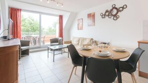 Een moderne eetruimte met een ronde tafel, zwarte stoelen en uitzicht op het omliggende landschap door grote ramen.