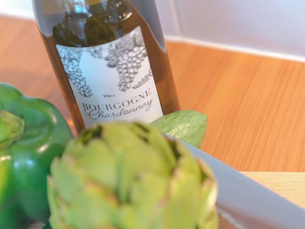 Uma garrafa de Bourgogne Chardonnay sobre uma mesa de madeira com alcachofras verdes.